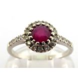 A ruby and diamond cluster ring, the central ruby approx. 0.5 carat, in a surround of small