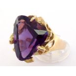 An amethyst dress ring, the large triangular cut stone 2.2cm long, cradled in a textured nest mount,