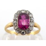 A ruby and diamond cluster ring, the central oval cut ruby approx. 0.92 carat, in a surround of