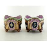 A pair of Victorian majolica planters, each on three architectural capital feet, the bowls with