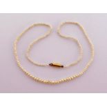 A child's seed pearl necklace, composed of small graduated pearls, 34cm long, to a barrel clasp,