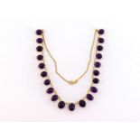 An 18 carat gold and amethyst necklace, composed of a fringe of graduated amethyst cabochons, to a