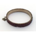 A Bohemian garnet bangle, set with four rows of small garnet, 11mm wide, mounted in white metal,