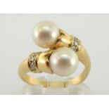 A cultured pearl and diamond ring, the cross over bezel terminating in two round 7.4mm pearls,