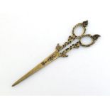 A pair of antique brass tailor’s scissors decoratively shaped and pierced through the arms and