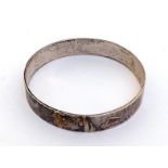 A silver bangle, of contemporary design, set with geometric pink gold motif about the circumference,