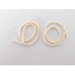 Two strands of uniform cultured pearls, the round pearls 7.4mm diameter, cotton strung, no clasps
