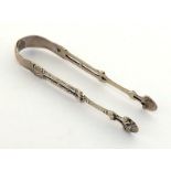 A pair of George III cast arm silver sugar tongs by Stephen Adams, London, circa 1770, the pierced