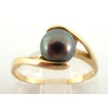 A cultured black pearl ring, the round central pearl 6.8mm, the shank stamped '14k', finger size Q/