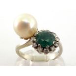 A diamond, emerald and cultured pearl ring, the cross over bezel set to one side with a 6.8mm