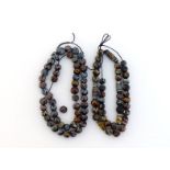 Two glass bead necklaces, composed of spherical black patterned beads, leather strung, 27 and 25cm