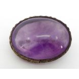 A Chinese export silver and amethyst brooch, the large oval cabochon 33 x 25 x 12mm, within a