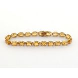 A citrine line bracelet, composed of uniform oval cut 7 x 7mm citrines, mounted in yellow metal, the