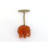 A carved amber pendant, modelled as an elephant, suspended from a gilt metal brooch, 3cm high, 10.