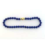 A lapis lazuli bead necklace, composed of uniform spherical 10mm beads, to a gold and enamel