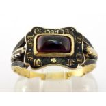 A late Georgian enamel and garnet mourning ring, the central rectangular cabochon garnet (