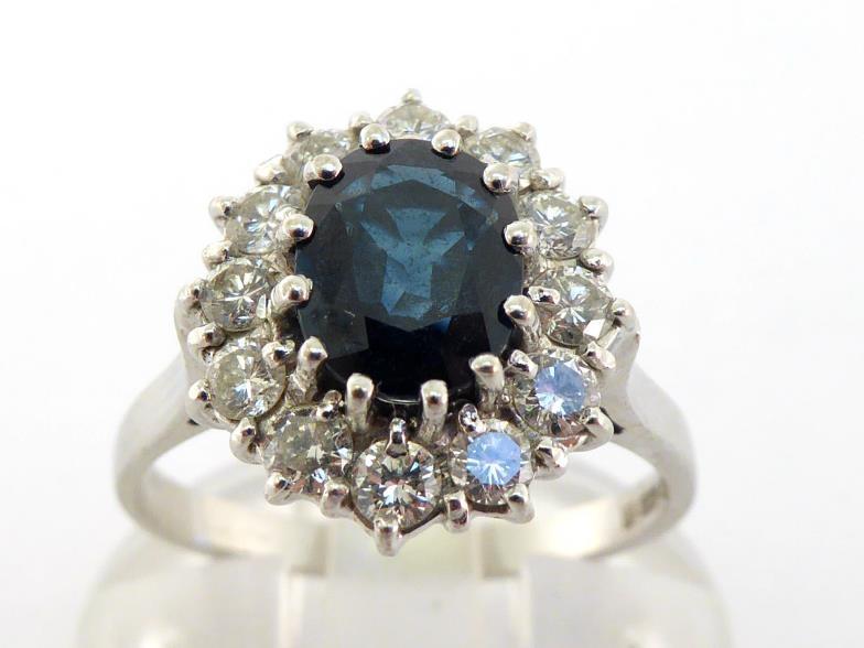A sapphire and diamond cluster ring,the central oval cut stone 7 x 6 x 2.8mm, in a surround of