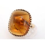 A 9 carat gold and amber dress ring, the domed cabochon stone 15.6 x 19.2mm, the shank fully