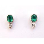 A pair of emerald and diamond ear studs, each stud set with an oval cut emerald, a small rub over