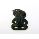 A New Zealand nephrite Hei Tiki pendant, the rims of the eyes painted red, 5.3cm long CONDITION: