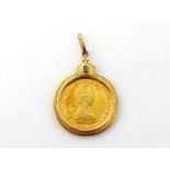 A gold pendant, set with a 1979 Canadian dollar coin, the bale stamped '750' and set with an emerald