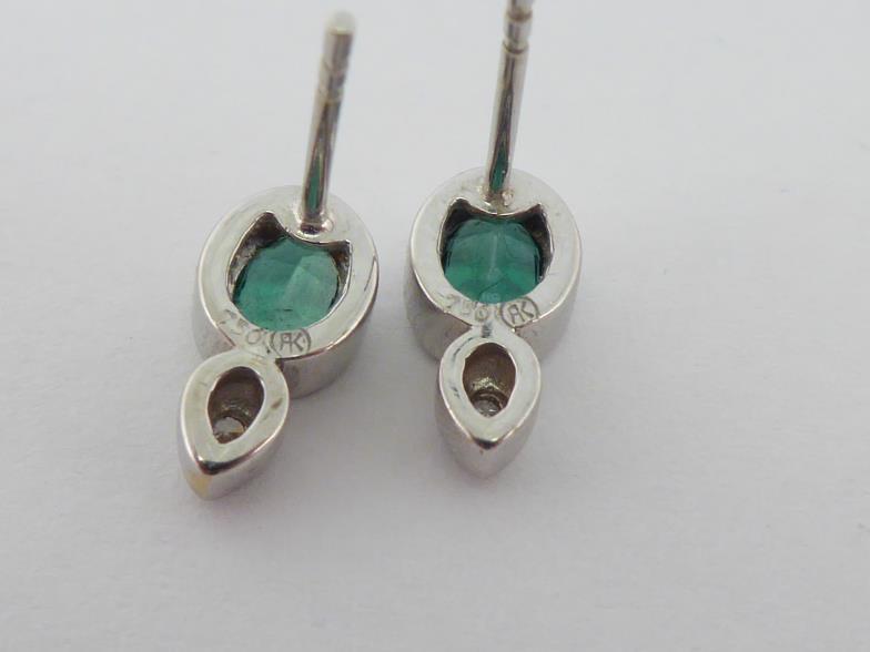A pair of emerald and diamond ear studs, each stud set with an oval cut emerald, a small rub over - Image 2 of 2