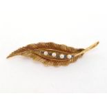A cultured pearl and sapphire brooch, modelled as a leaf, a line of alternate pearls and small
