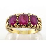 An 18 carat gold and ruby ring, the three oval cut stones claw set to a raised scroll mount, the