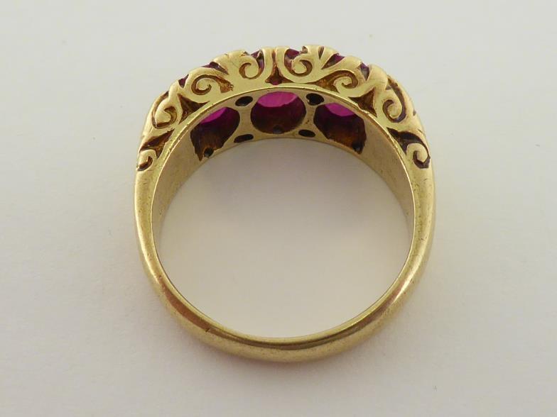 An 18 carat gold and ruby ring, the three oval cut stones claw set to a raised scroll mount, the - Image 3 of 5