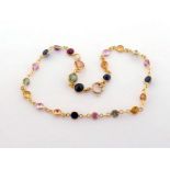 A dainty multigem bracelet, spectacle set along its length with various stones to include ruby and