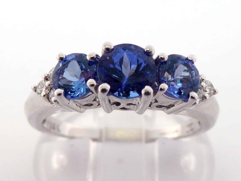 A 14 carat white gold, tanzanite and diamond ring, set with three graduated central round cut