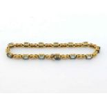 An aquamarine and diamond line bracelet, composed of alternate oval cut aquamarines and pairs of