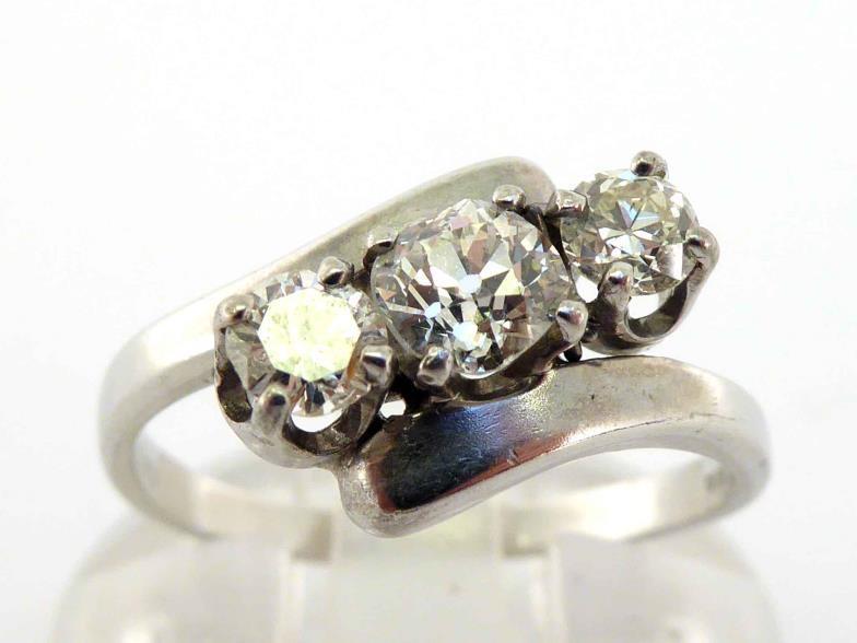 A three stone diamond ring, obliquely set with three tapering old cut brilliants totalling approx.