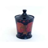 A Moorcroft ceramic tobacco jar in the Pomegranate pattern on a dark blue ground, circa 1915, the