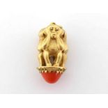 A 'three wise monkeys' gold and coral pendant, the circular coral cabochon to the base 12.5mm