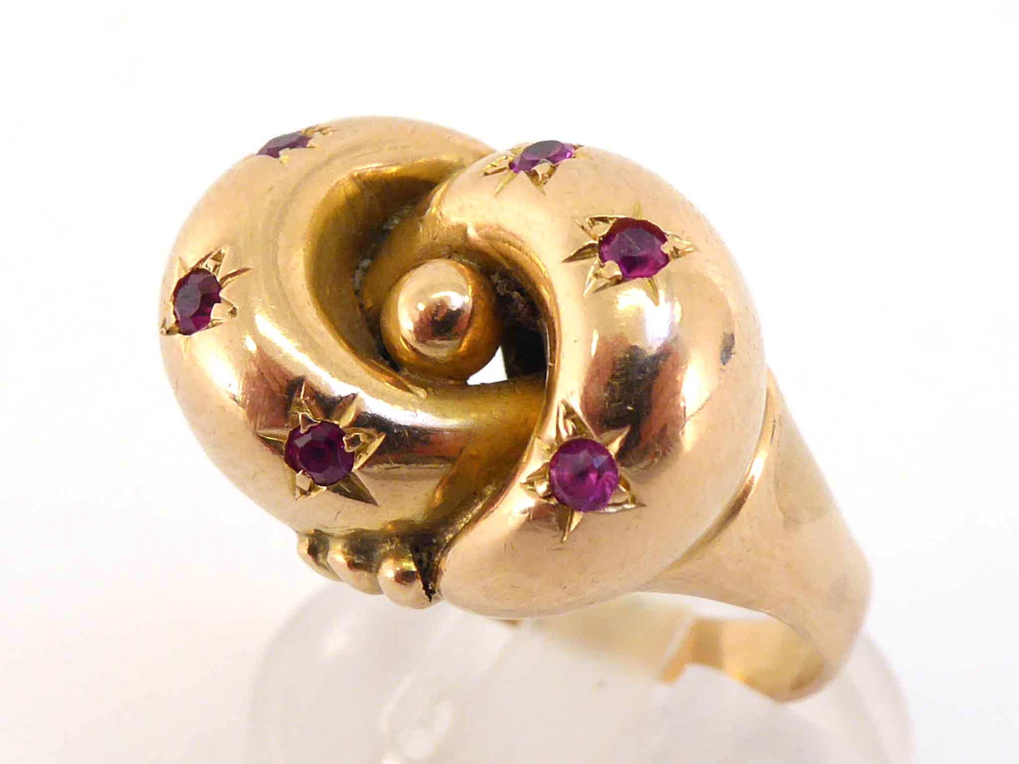 A Victorian gold and ruby knot ring, the central motif set with small round cuts, the shank