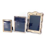 Three modern silver-fronted photograph frames, one shaped oblong with border of scrolls and
