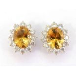 A pair of 18 carat gold, citrine and diamond earrings, each central oval cut 11 x 9.1mm, in a