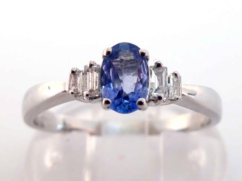 A tanzanite and diamond ring, the central oval cut tanzanite 6 x 4mm, between two pairs of graduated