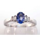 A tanzanite and diamond ring, the central oval cut tanzanite 6 x 4mm, between two pairs of graduated