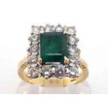 An 18 carat gold, emerald and diamond cluster ring, the central emerald cut stone 7.7 x 6.4 x 3.8mm,