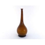 A tall-necked onion-shaped brown glass bottle on spread base with vestiges of long trailed glass