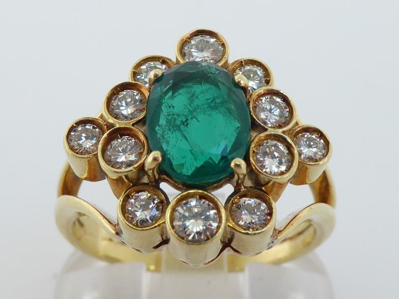 An emerald and diamond cluster ring, the central oval cut 8.4 x 6.6 x 3.2mm, in a surround of deep - Bild 2 aus 3