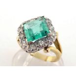 An emerald and diamond cluster ring, the rhombus cut 8.6 x 8.6 x 5mm, in a surround of brilliants,