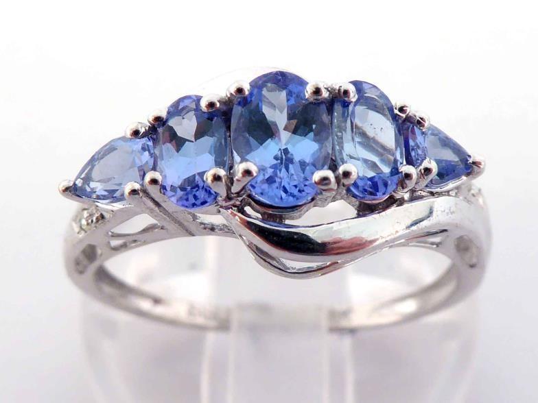 A 14 carat white gold and tanzanite ring, set with five graduated oval and pear cut stones, the