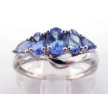 A 14 carat white gold and tanzanite ring, set with five graduated oval and pear cut stones, the