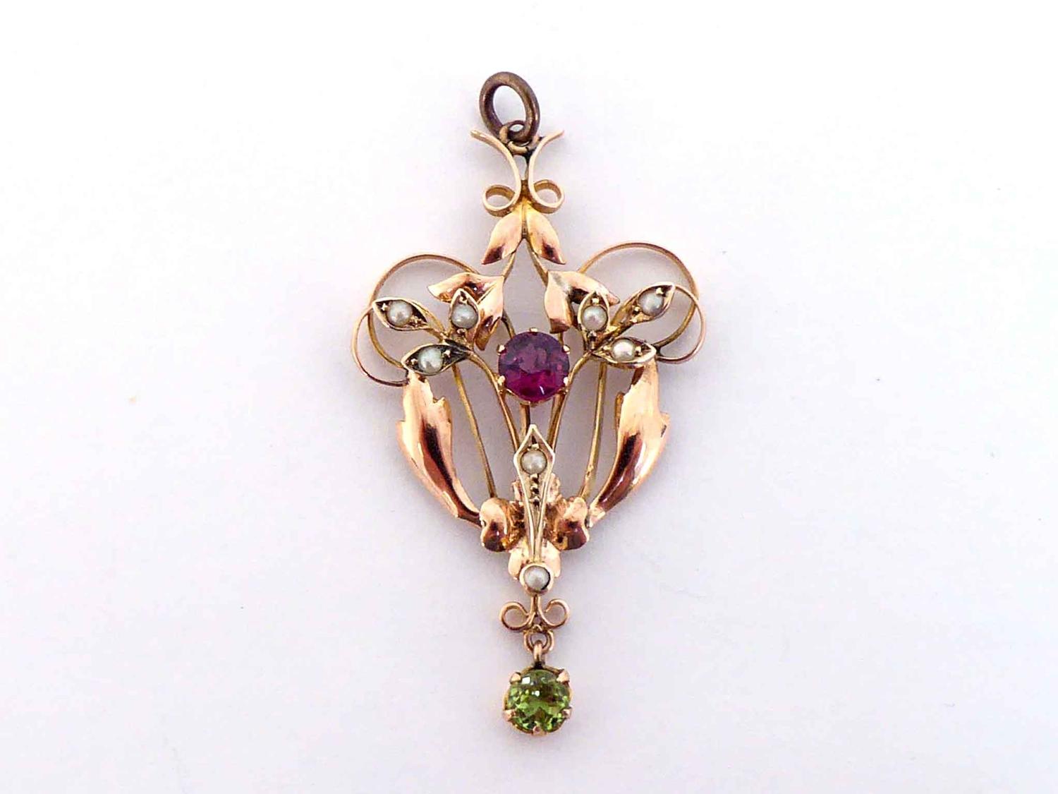 An Edwardian garnet, peridot and seed pearl pendant, the central round cut garnet 4.8mm, within a