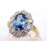 A sapphire and diamond cluster ring, the central oval cut stone 8.9 x 6.2 x 3.5mm, in a surround