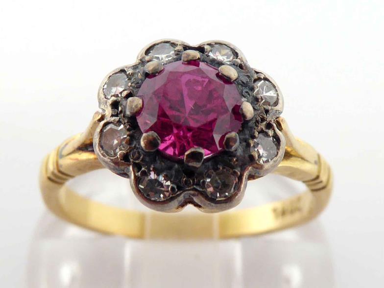 A mid 20th century synthetic ruby and diamond cluster ring, the central round cut ruby 5.4mm, in a