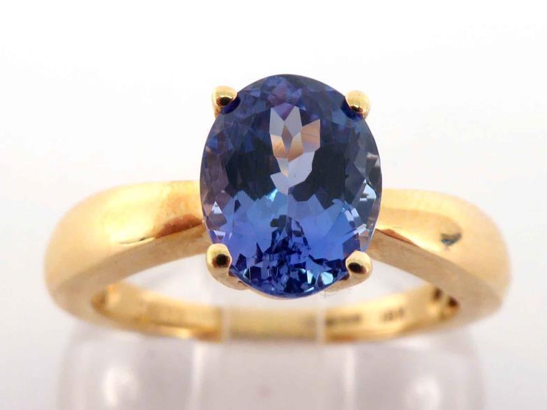 An 18 carat gold and tanzanite ring, the central oval cut stone approx. 2 carats, the shank fully